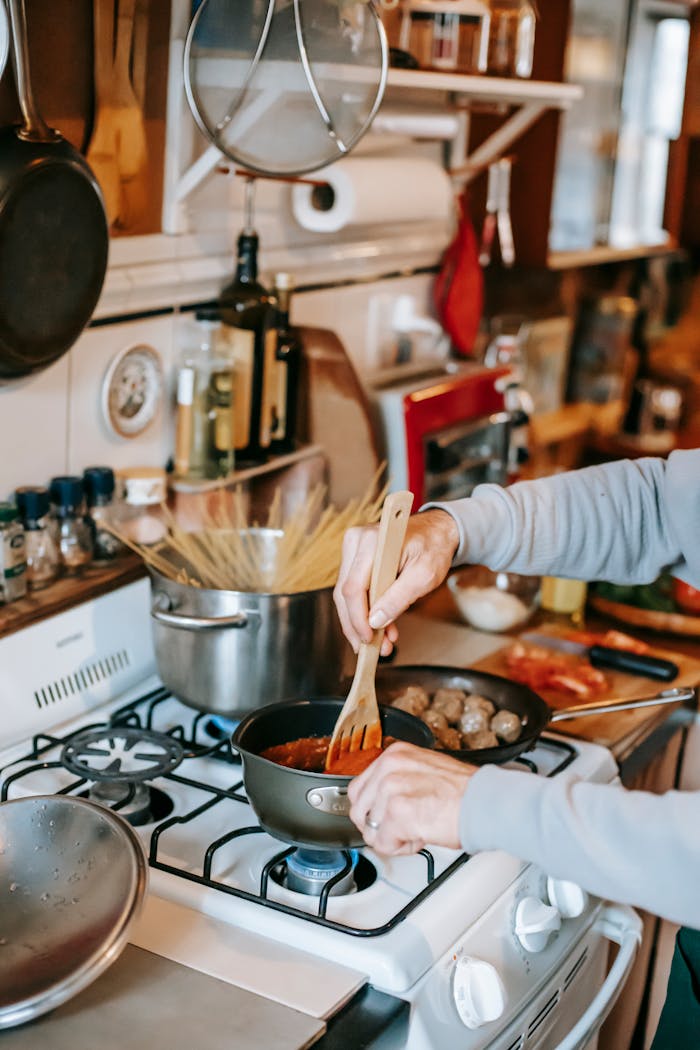 why-choose-us-01 A person stirs homemade tomato sauce while cooking pasta and meatballs on a stove.